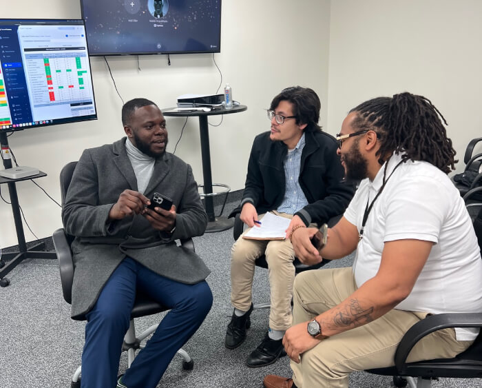 Three professional experts collaborating on a local GBP strategy while reviewing data analytics on a screen in a corporate workspace.