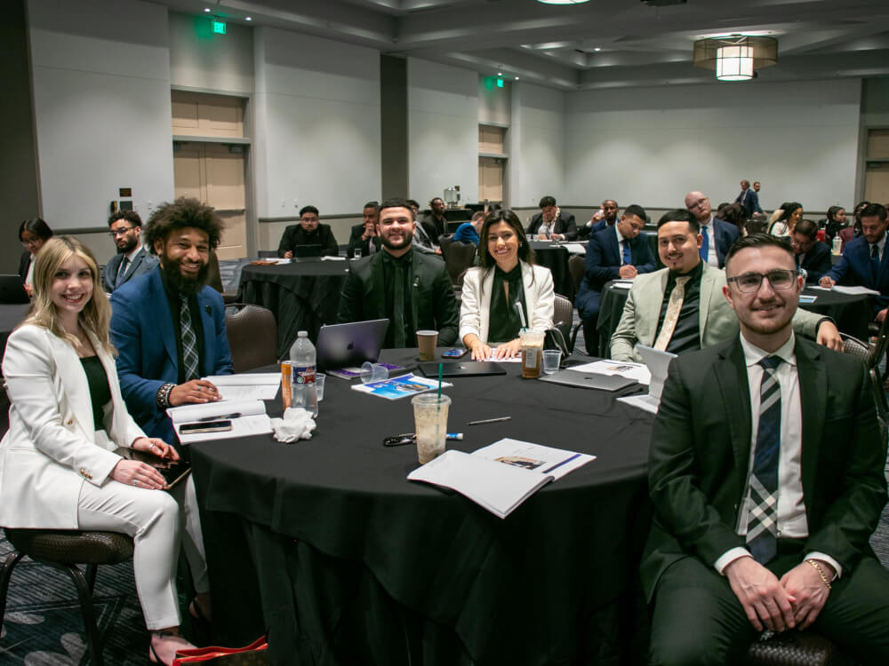A group of professional marketing and sitting at a round table during a corporate training workshop or industry conference.