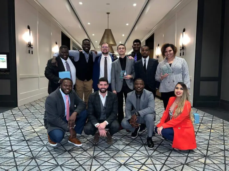 A diverse group of professional marketing and SEO specialists posing together with awards in a modern hotel lobby during a corporate gala.